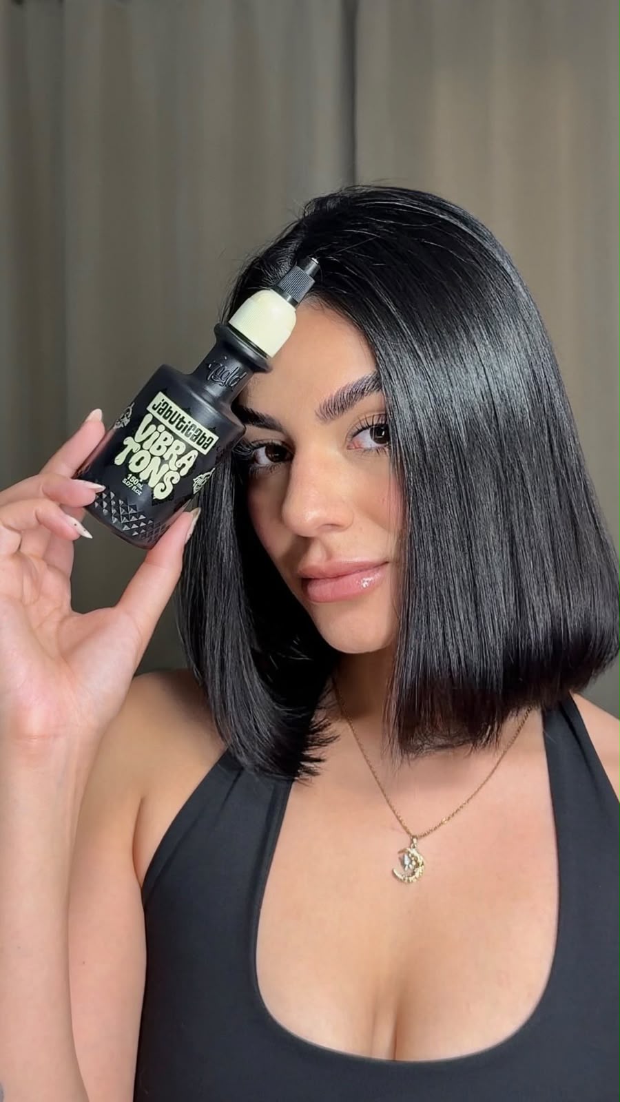 Mulher com cabelo preto curto segurando Vibra Tons